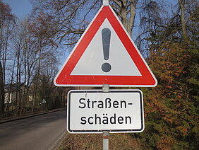 Verkehrszeichen Achtung - Ausrufezeichen mit roter Umrandung und Zusatzschild Straßenschäden